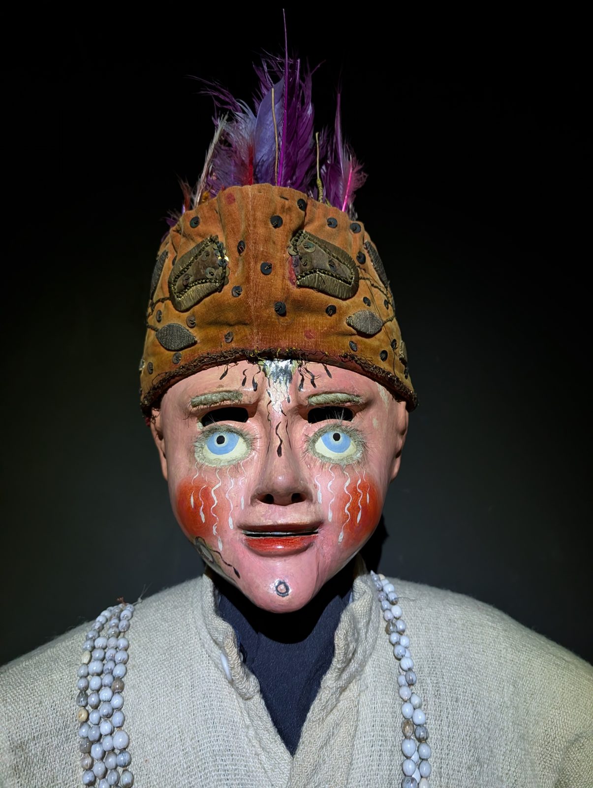 A pale face under feathers, from a dance of the lowlands.