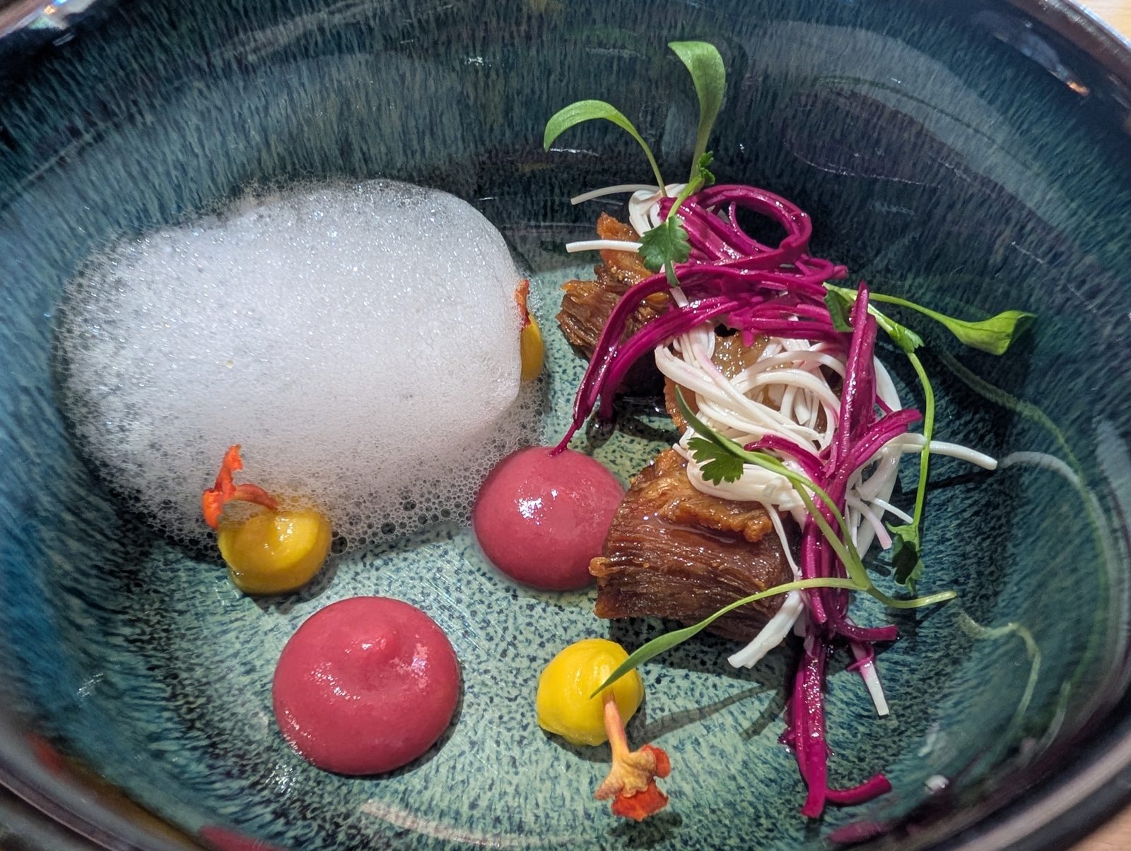 Foam, beet spheres, and a shredded salad under them.