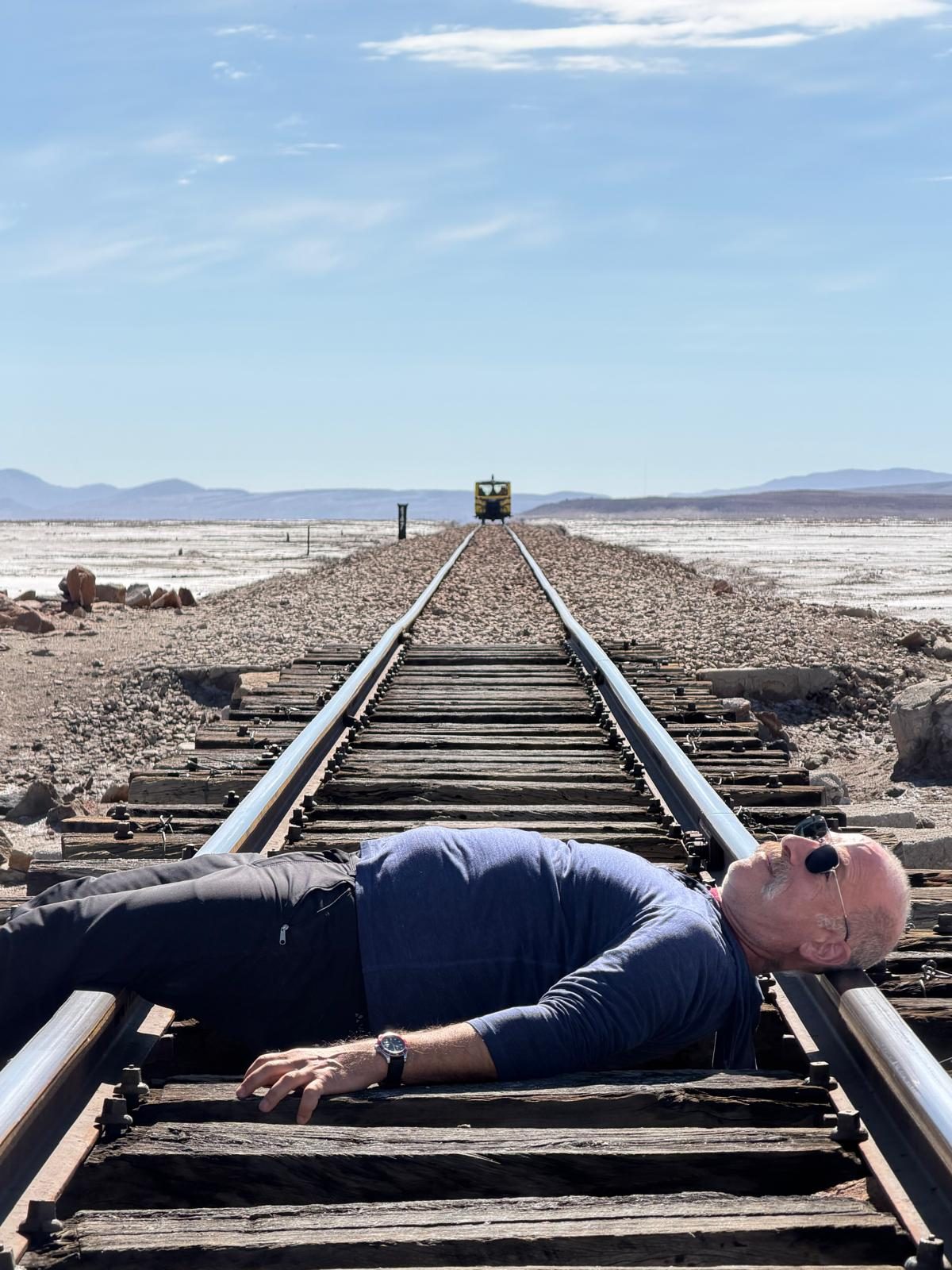 Lying on the rails. That dot on the horizon is a one-car train, and it was coming.